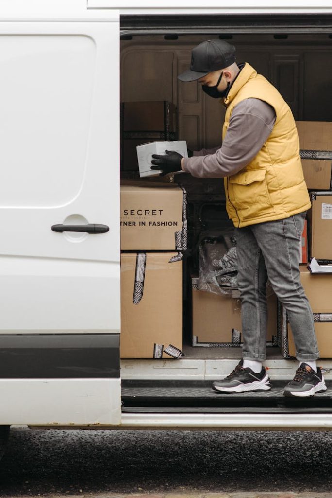 Deliveryman arranging packages in white van for efficient distribution.